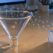Métaphore visuelle de demandes de rendez-vous qui se perdent dans un entonnoir commercial transparent sur un bureau professionnel.